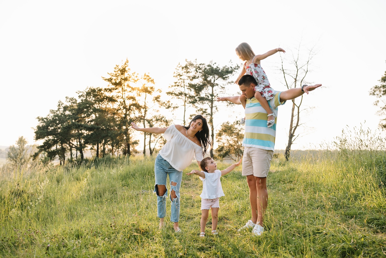 Smiling family with two children, rest and have fun in nature. Concept of happy and balanced life that is a result of applying Gyana modern Ayurveda application techniques and practices.