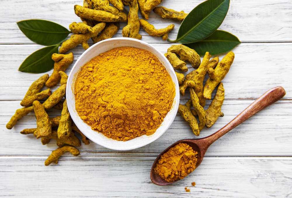 Bowl with turmeric powder and dry roots on a wooden background, blood pressure remedies