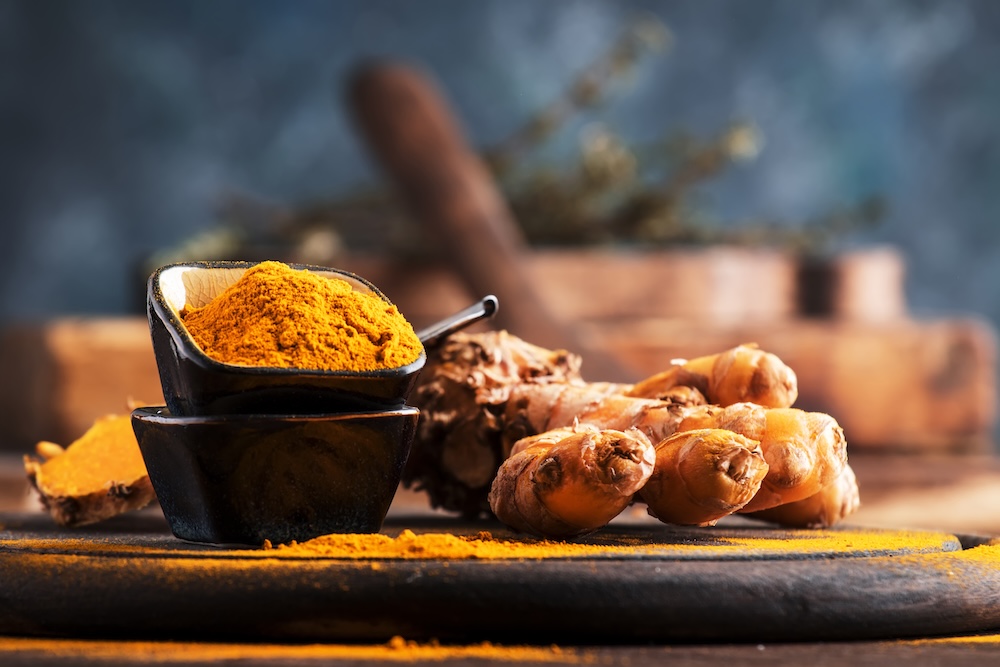 Turmeric powder and fresh turmeric on wooden background, haldi - a great antiseptic and multi-remedy spice in ayurveda, a must-have kitchen spice