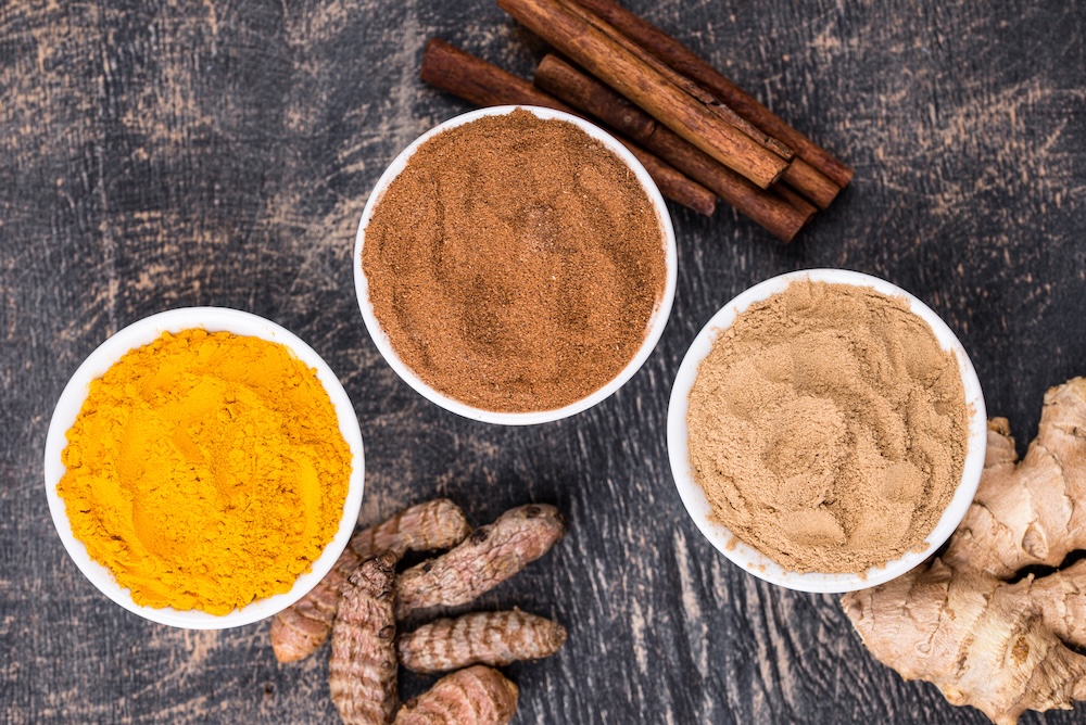 Turmeric, ginger and Cinnamom on the wooden table featuring dry roots and spices as dry powder. Autumn Ayurvedic warming and balancing spices, vedic recipes and culinary ancient secrets for health and wellbeing.